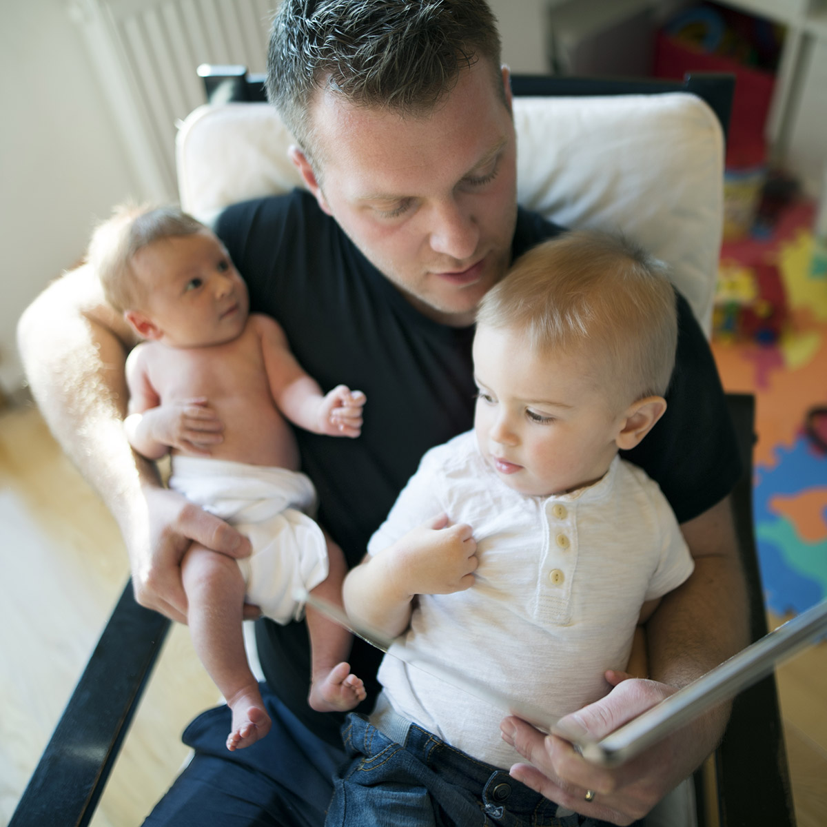 Father reading a book to twin babies
