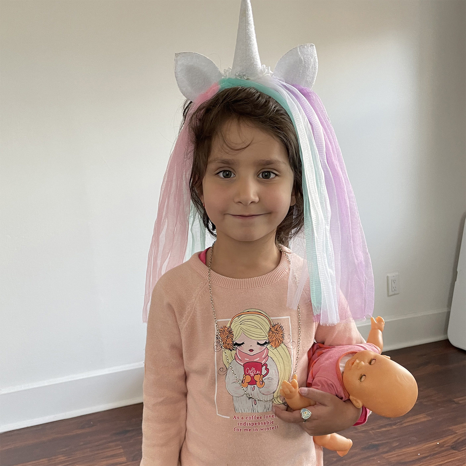 Rajwa holding a doll, wearing a unicorn headband