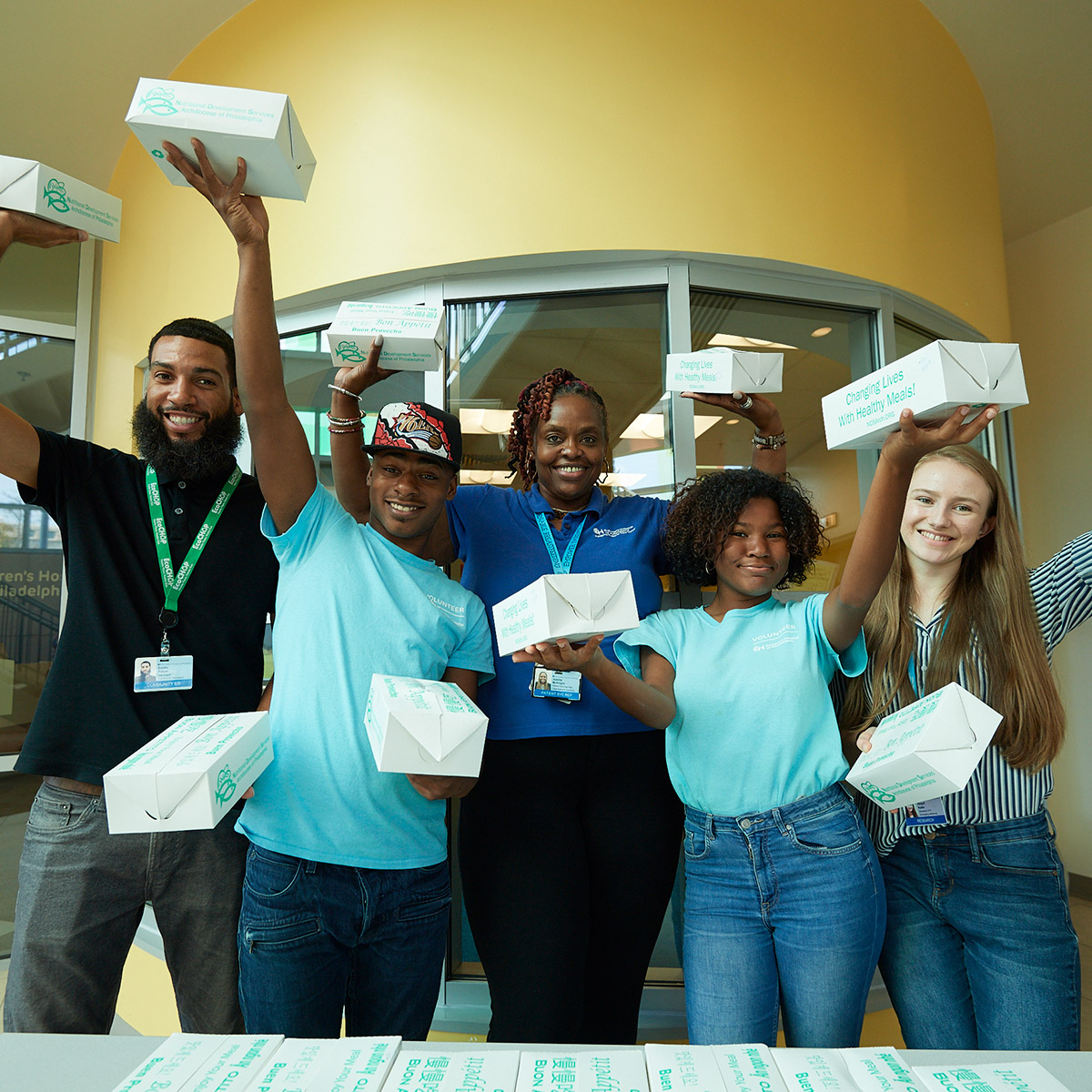 Group of volunteers holding up lunch boxes