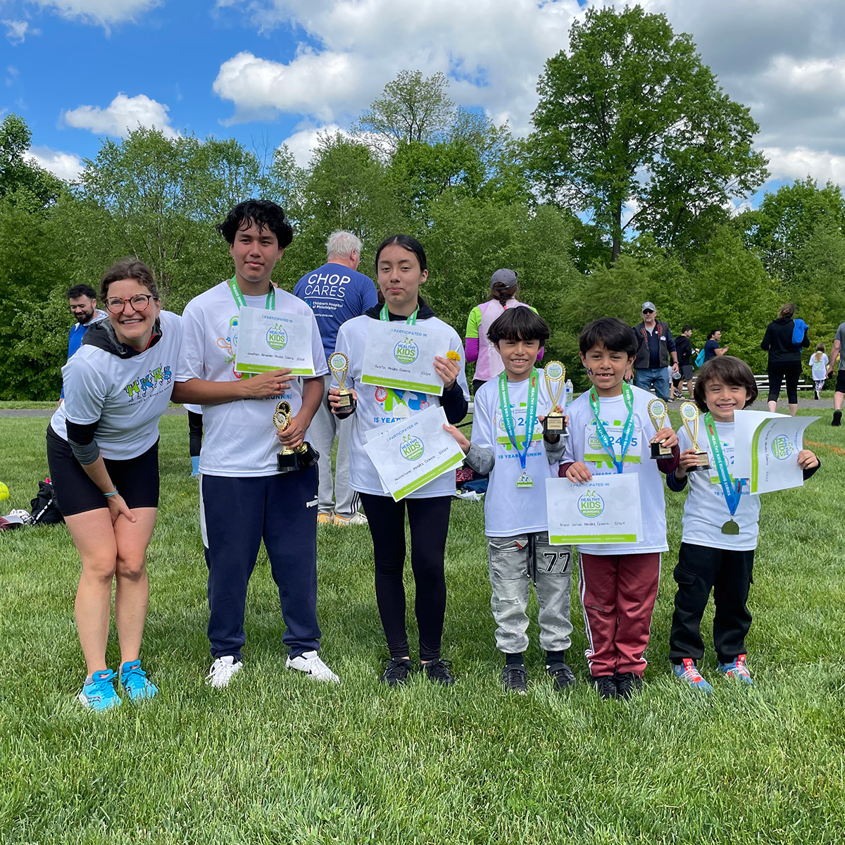 Children showing off their Healthy Kids Running Series medals, trophies, and certificates