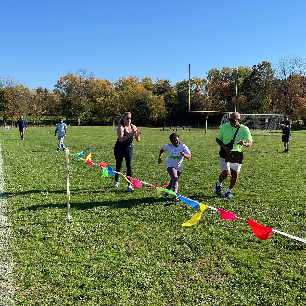 Child running with cheering volunteers at his side