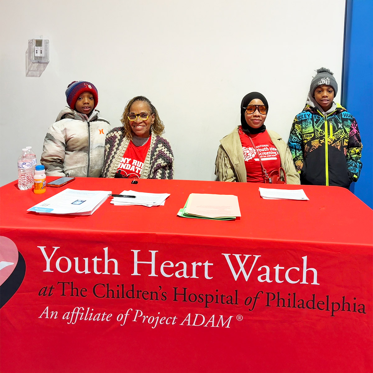 Volunteers sitting at a Youth Heart Watch table