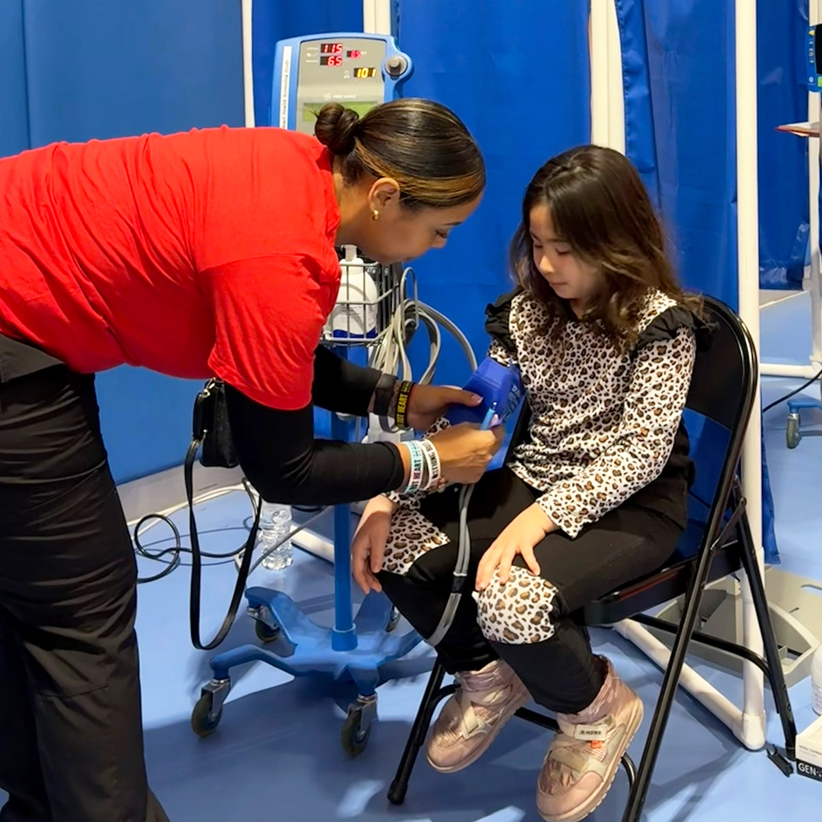 Young girl having her blood pressure tested by a volunteer